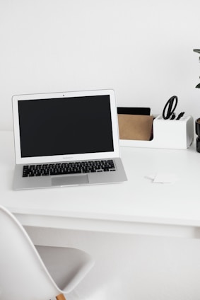 Minimalist black and white photo of a calm workspace with a laptop and organized notes.