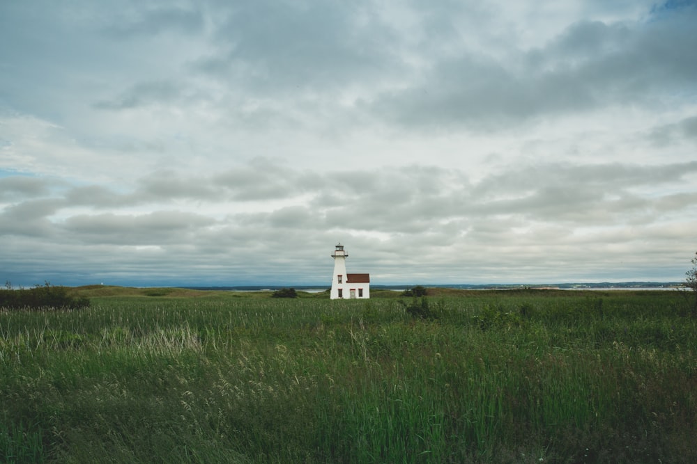 white lighthouse surrounded by grass field