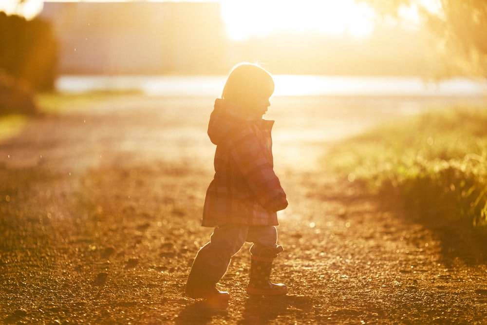 girl walking on ground towards grass