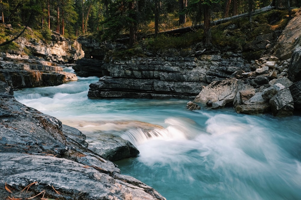Photographie en accéléré d’une rivière qui coule entourée de roches grises