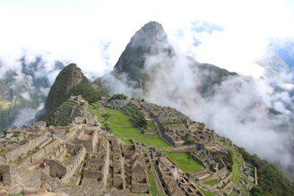 A panoramic view of the ancient archaeological site of Pacopampa surrounded by Andean mountains and local villagers in traditional clothing.