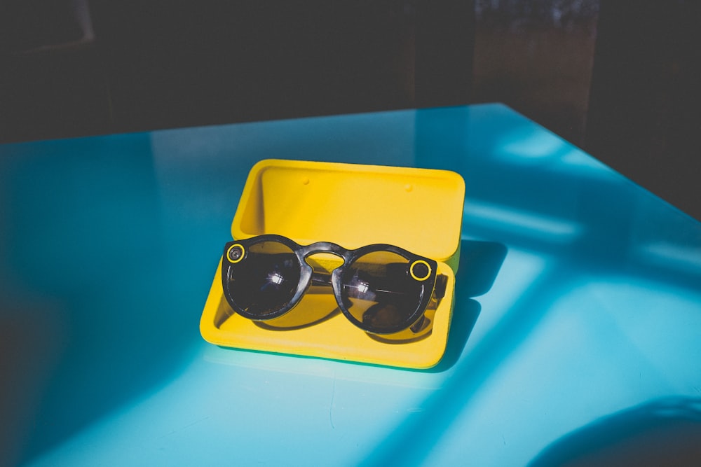 occhiali da sole neri in custodia gialla sul tavolo