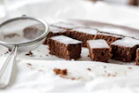 Close-up of a rustic chocolate zucchini cake with a dusting of powdered sugar on a wooden table.