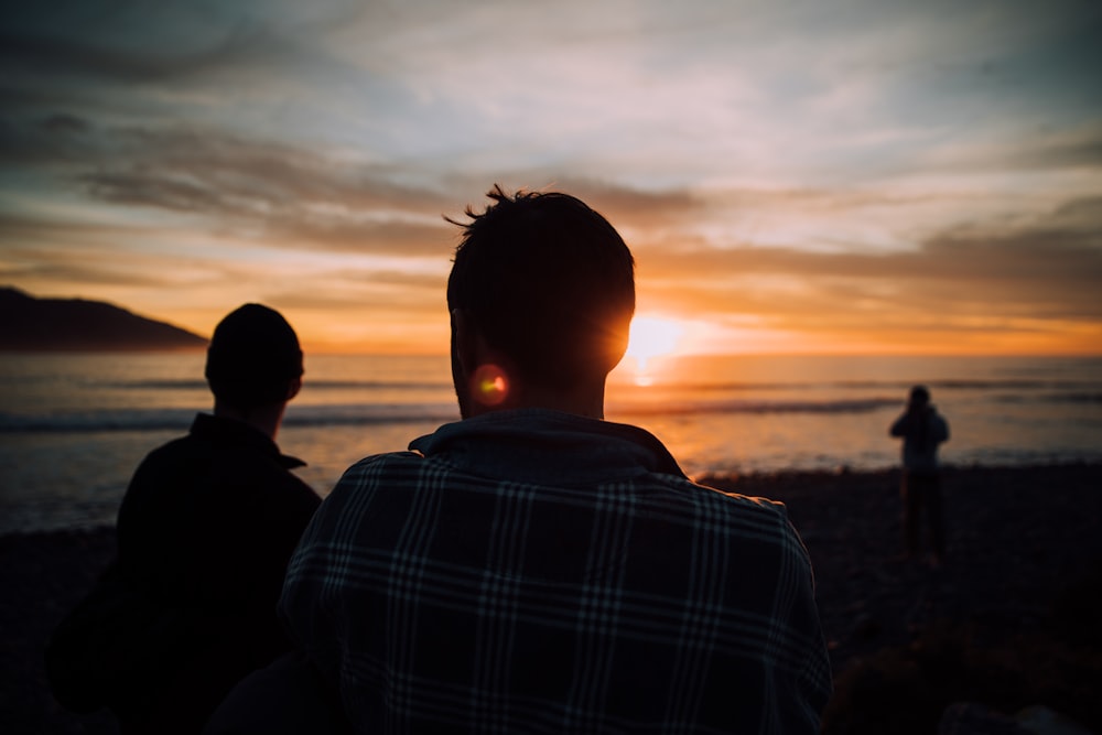 silhouette of tree people on shore during sunset