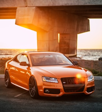 orange Audi coupe parked on gray concrete road