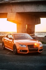 orange Audi coupe parked on gray concrete road