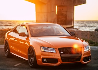 orange Audi coupe parked on gray concrete road