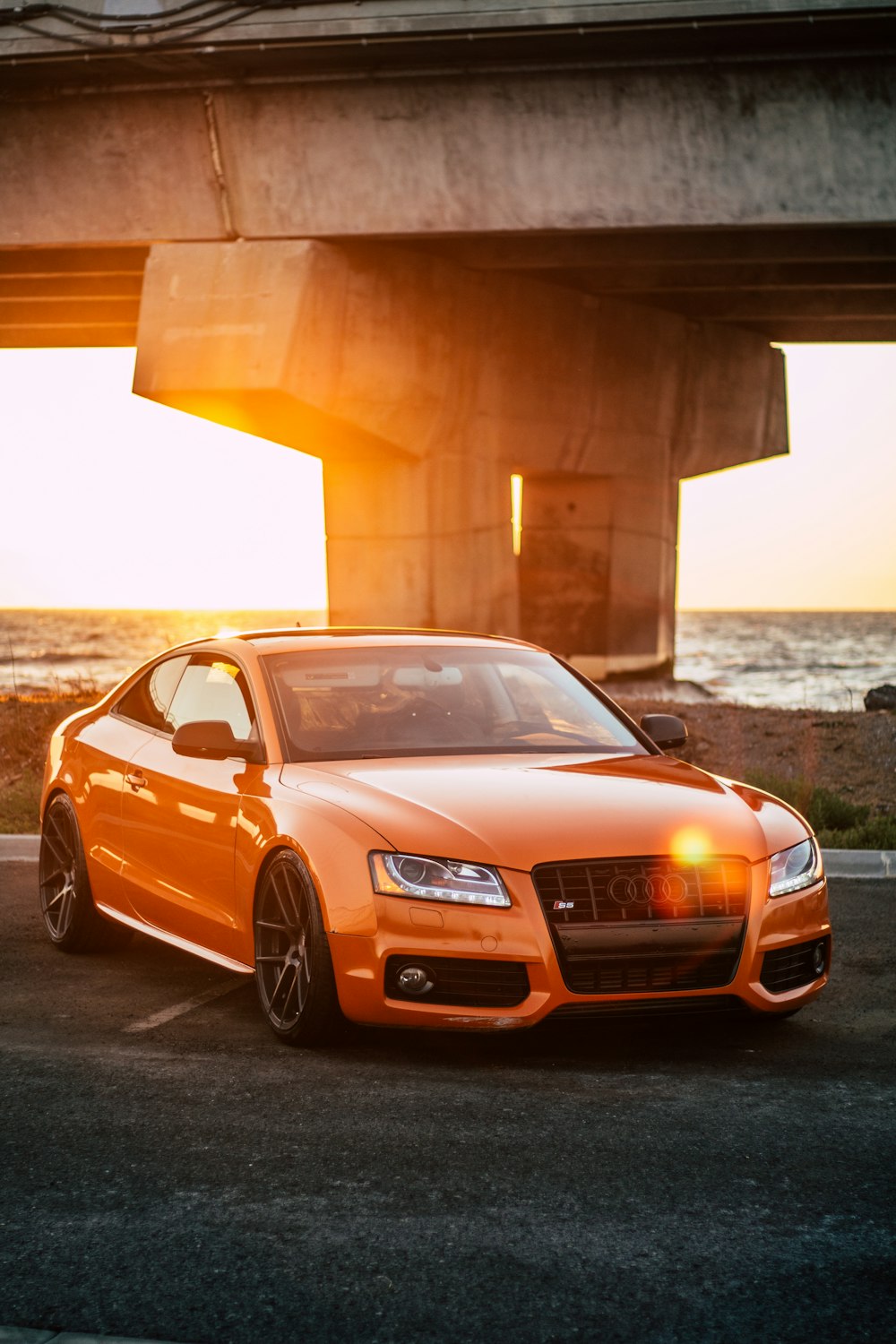 Audi coupé orange garé sur une route en béton gris