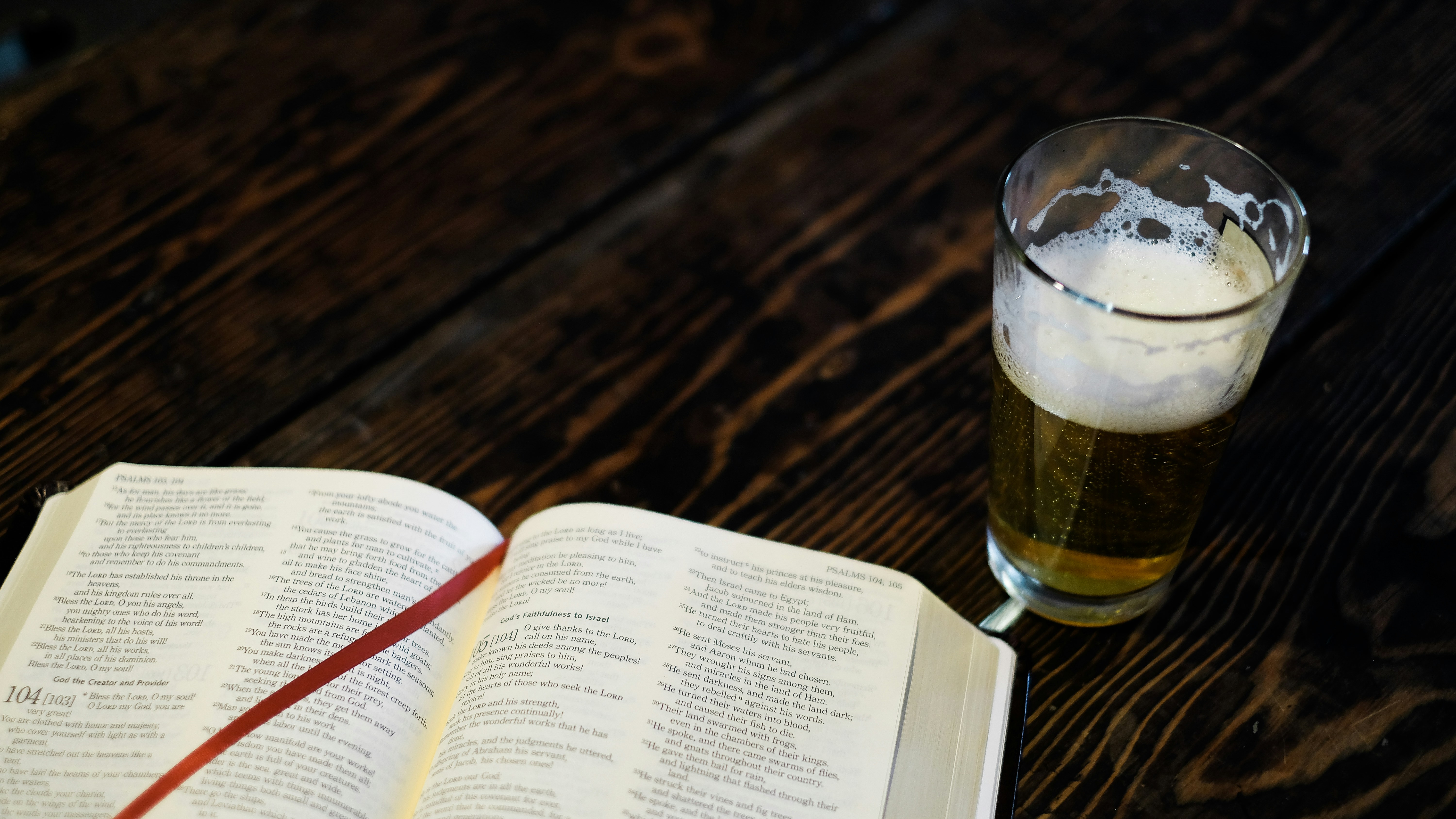 A large hardcover book next to a glass of beer.