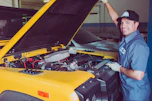 A smiling customer shaking hands with a technician beside their serviced vehicle.