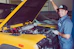 A friendly locksmith helping a satisfied customer with keys in a bright yellow and black uniform.
