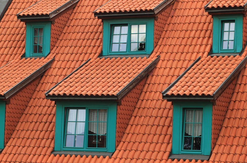 Finished pitched residential roof clad in clay tiles with dormer windows