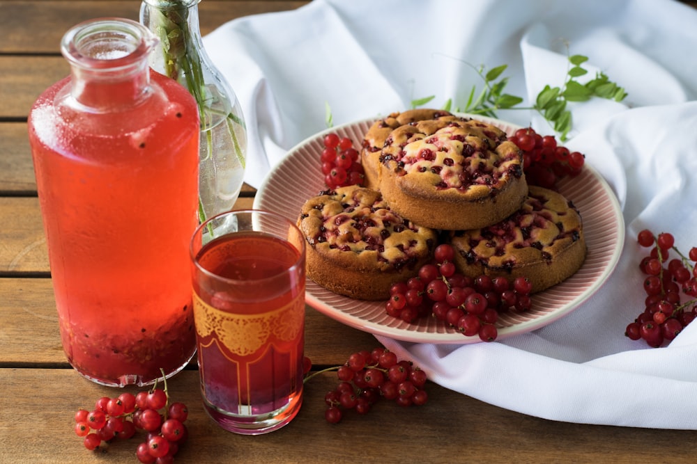 a plate of muffins next to a glass of tea