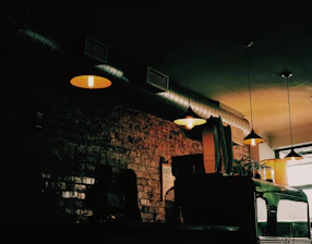 A cozy, dimly lit café interior with dark wood accents and soft glowing lights, featuring a barista using AI-powered equipment.