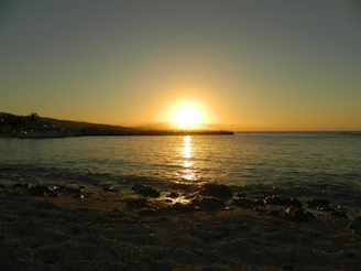 A golden sunset over a serene beach with a silhouette of a traveler holding a map.