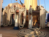 Stack of durable marine ropes coiled neatly on a dock under sunlight.