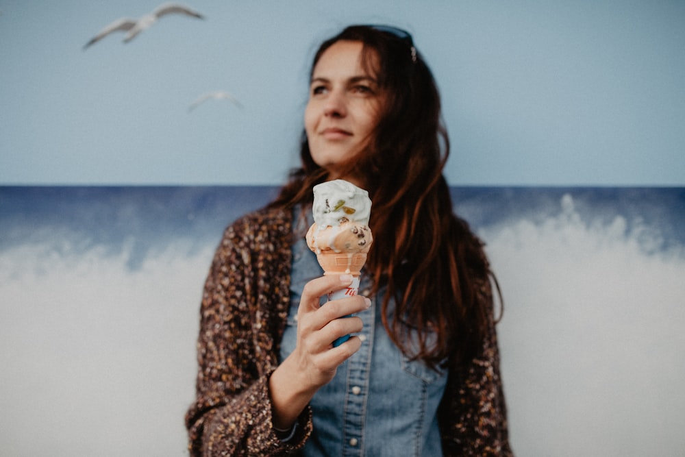 mujer sosteniendo helado frente a la ola
