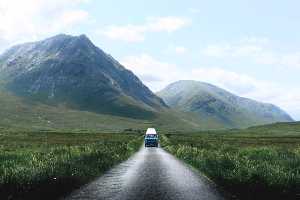 blue vehicle passing through grass field