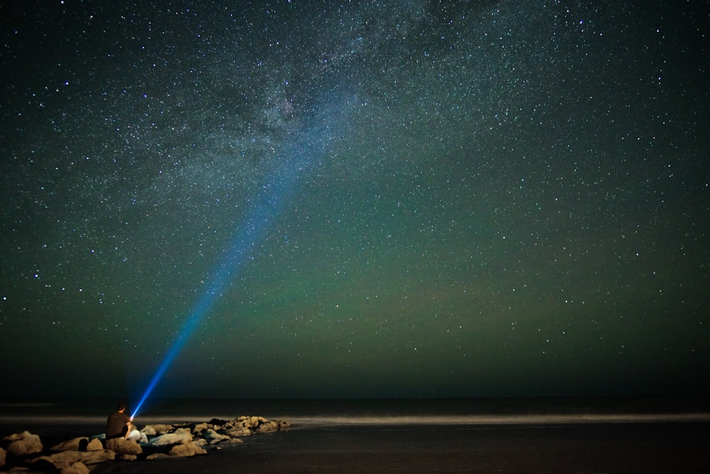 Langzeitbelichtungsfotografie einer Person, die nachts eine Taschenlampe eingeschaltet hält
