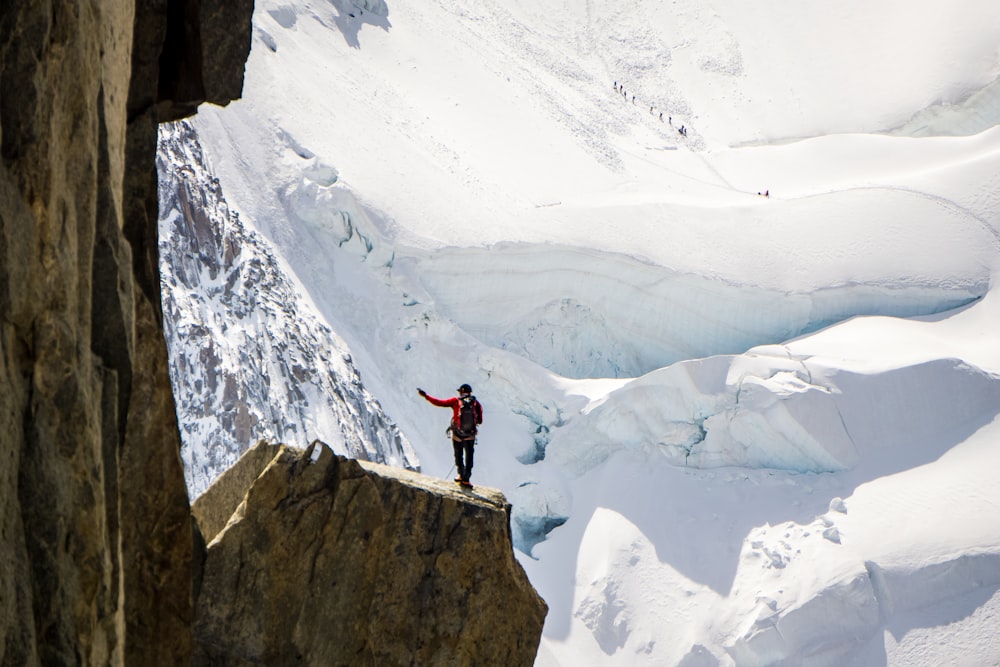 Persona che si leva in piedi sulla cima della montagna accanto a Snow Mountian