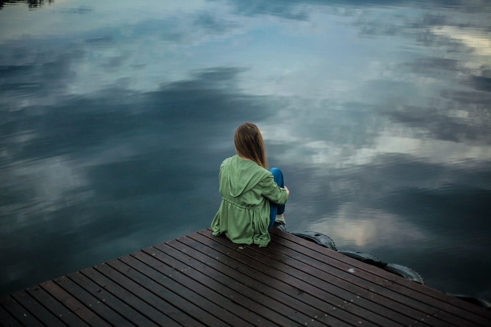 donna seduta sul molo vicino allo specchio d'acqua