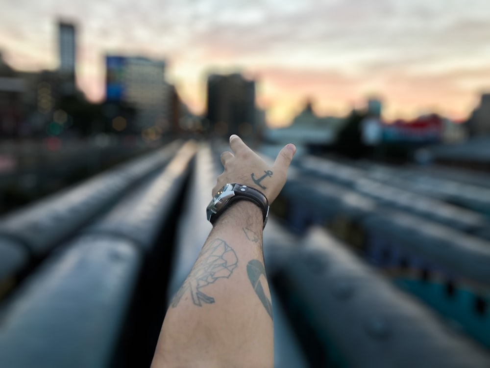 tilt shift photography of man's left hand pointing high-rise building