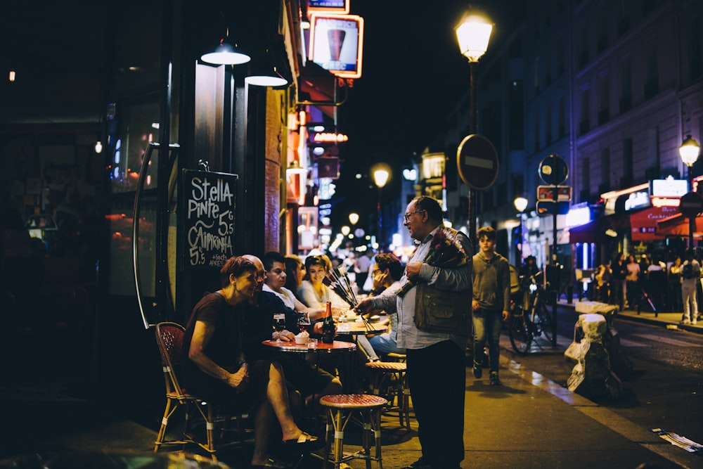 man in black jacket talking to man and woman