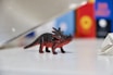 A colorful 3D printed dinosaur toy made by nisams, displayed on a wooden table.