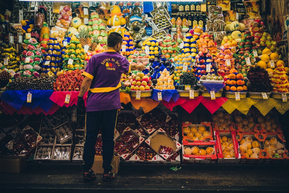 hombre de pie frente al puesto de productos agrícolas