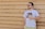 man wearing eyeglasses holding plastic cup standing in front of brown wall
