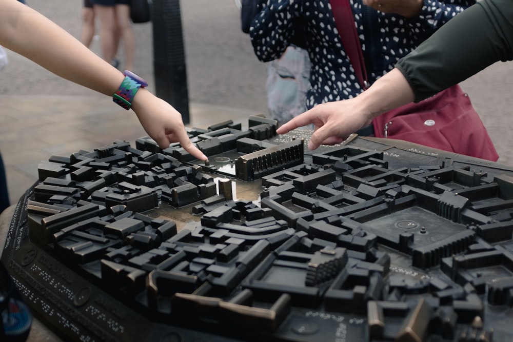 people holding black building bricks