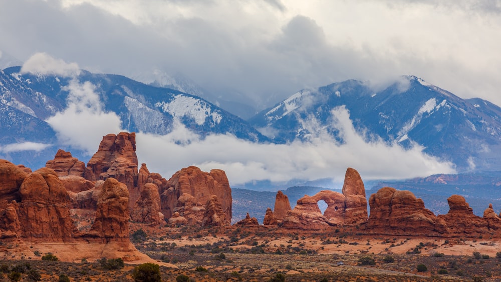 brown rock formation near mountain under cloudy sky