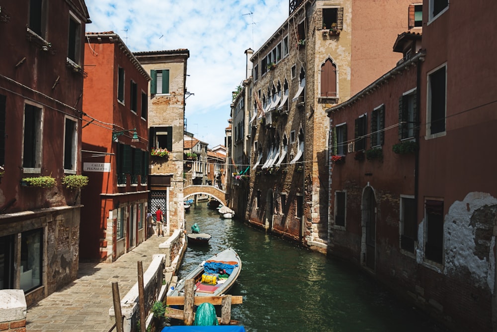 white motorboat on body of water between buildings at daytime