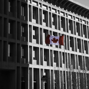 Modern assisted living building with Canadian flag fluttering nearby.
