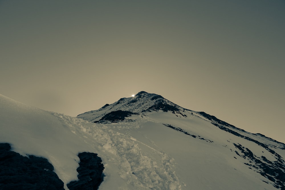 a snow covered mountain under a cloudy sky