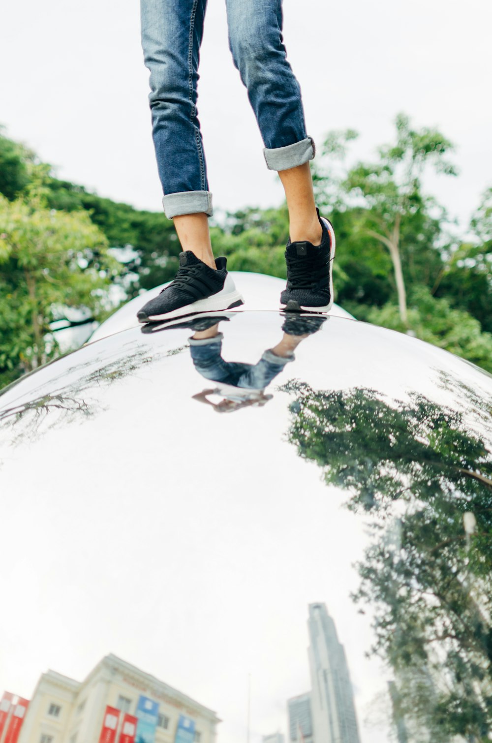 person wearing shoes and pants standing on chrome structure at daytime