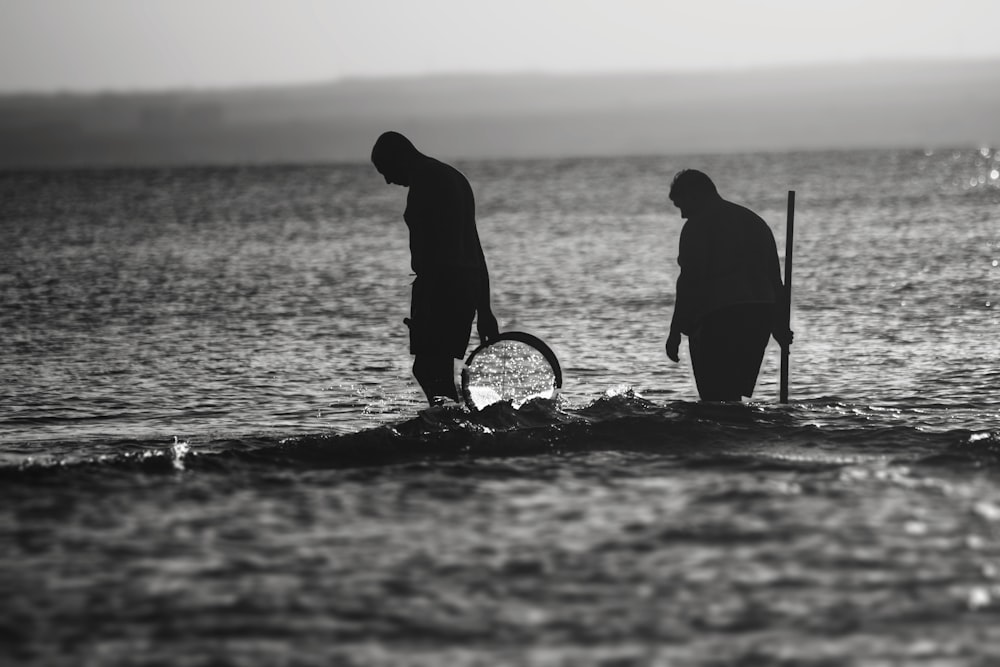 grayscale photography of men walking near shore