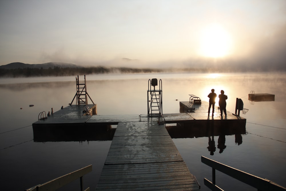 three people on wooden dock under the sun