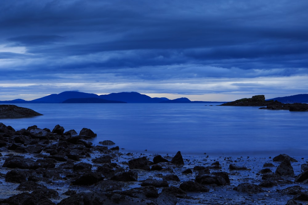 rocks on seashore under gray clouds