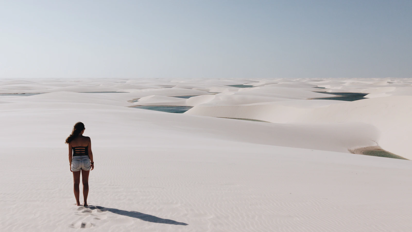 A walker on the white dunes between the lagoons — Lençóis Maranhenses, Brazil
