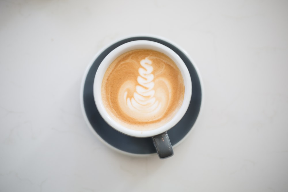 Graue und weiße Keramiktasse mit Kaffee-Latte-Kunst
