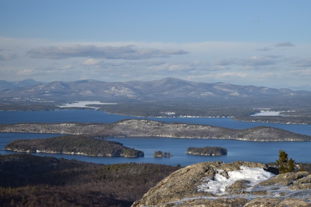 A panoramic view from a mountaintop overlooking a patchwork of forests and lakes.