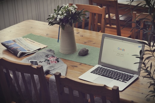 laptop on top of table beside vase of flowers