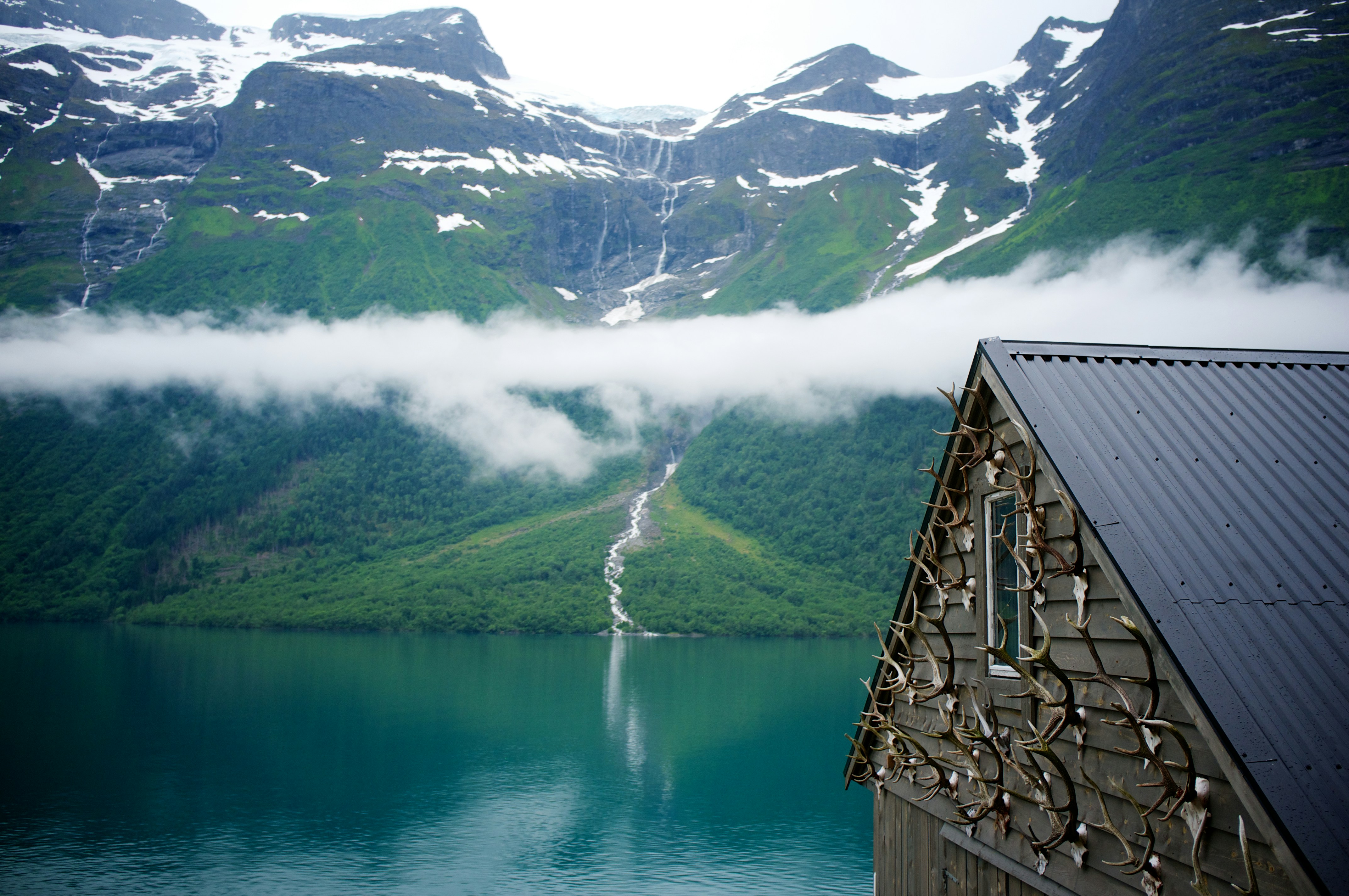 green mountain with waterfalls surrounded by body of water