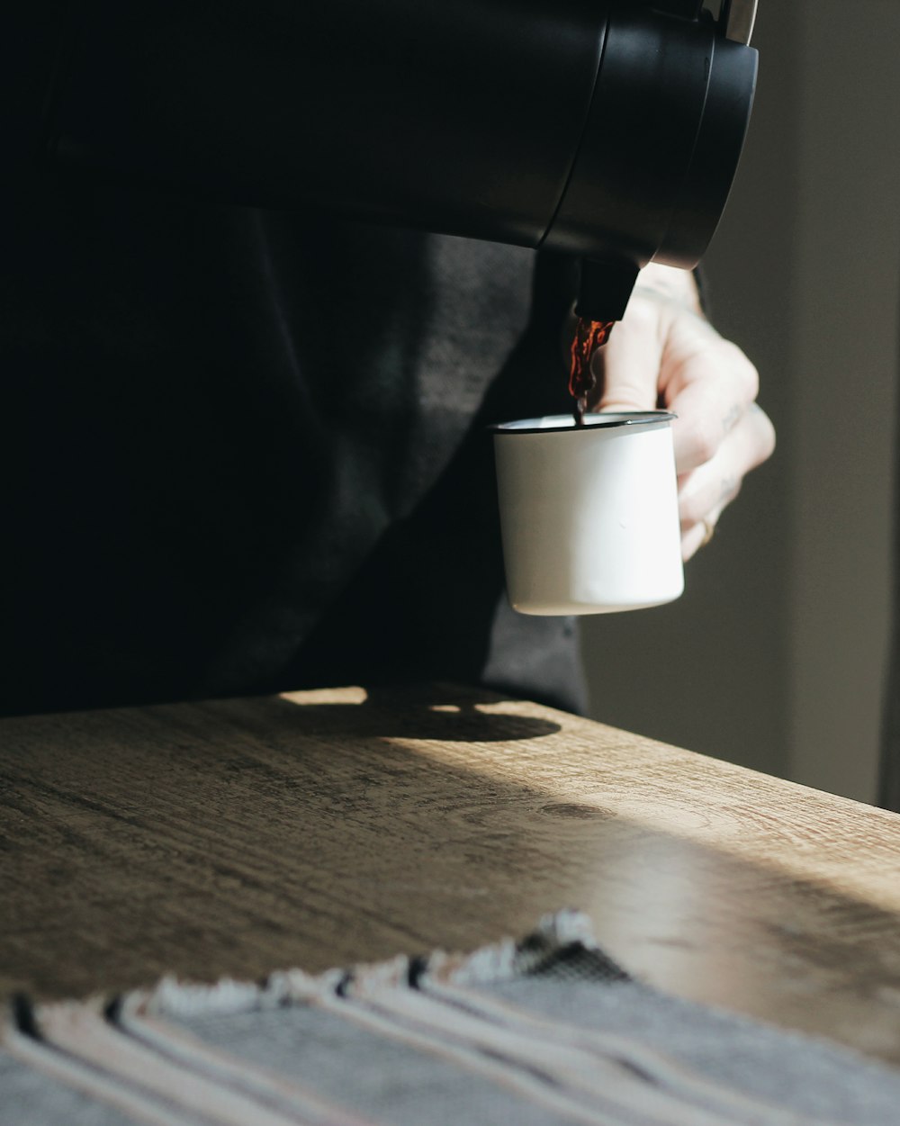 person pouring tea on mug