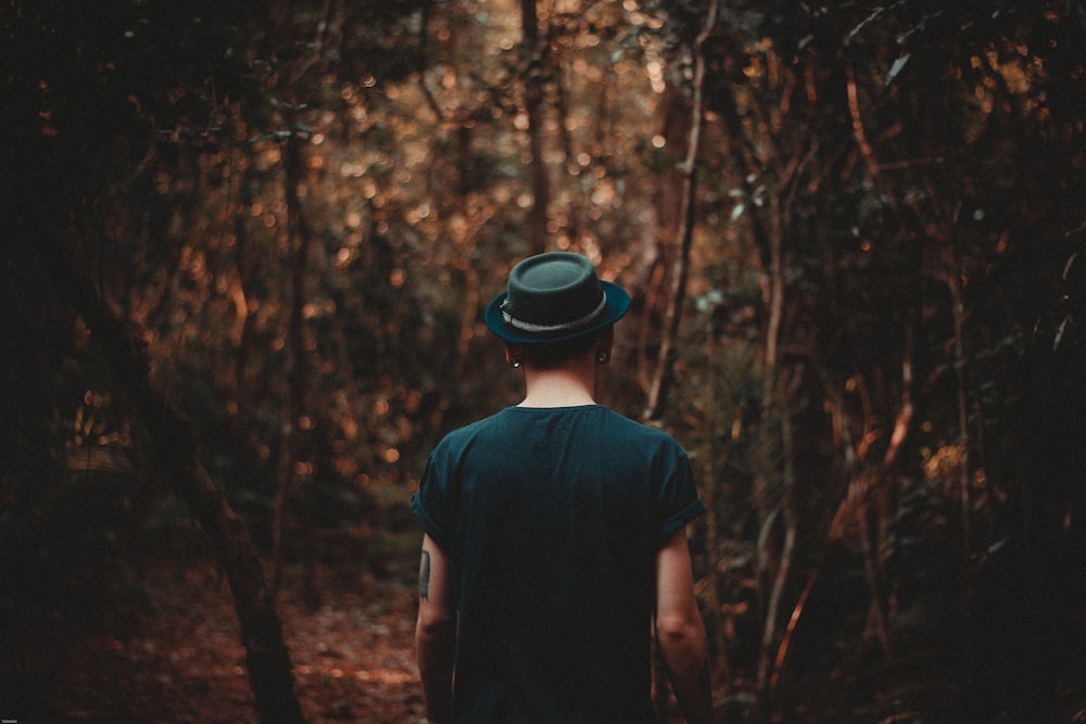 검은 모자를 쓴 남자가 낮에 숲을 걷고 있다.