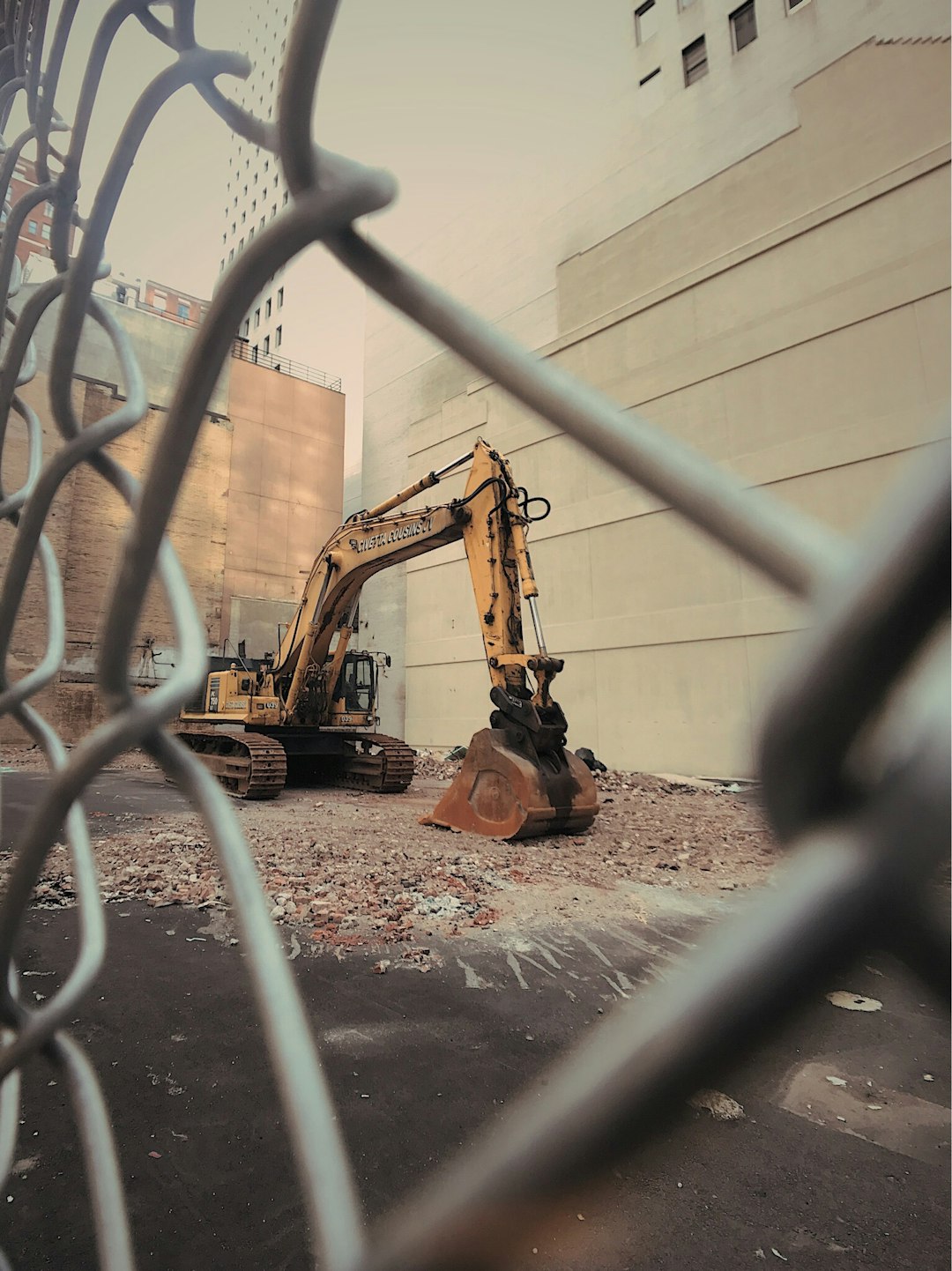 yellow excavator beside brown building