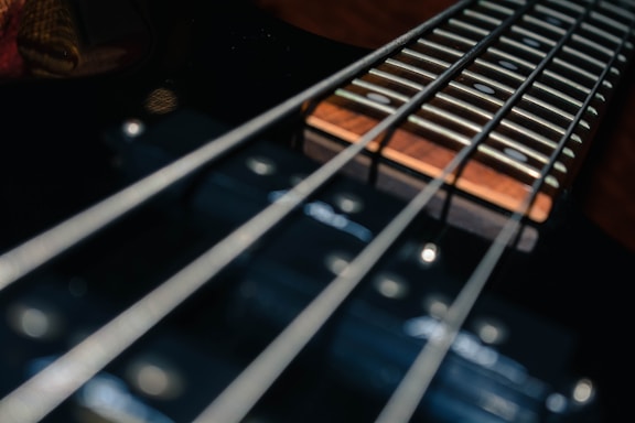 Close-up view of a guitar neck with strings tightly aligned over the frets, highlighting the detailed texture of the metal strings and the polished wood fretboard.