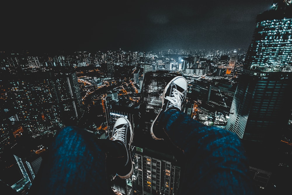 person wearing blue jeans facing cityscape during nighttime