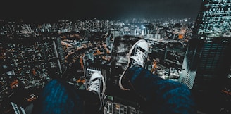 person wearing blue jeans facing cityscape during nighttime